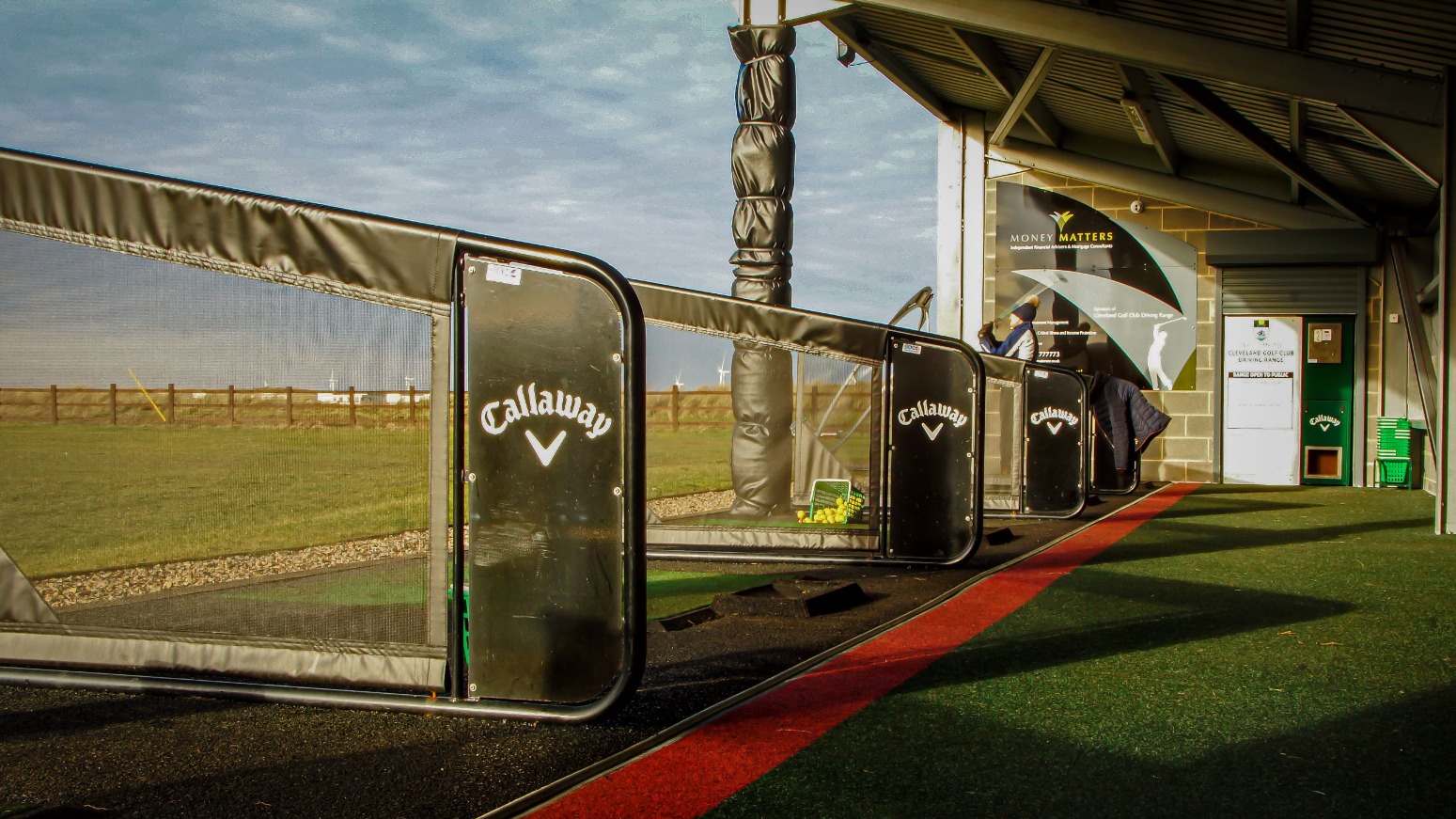Covered driving range bays at Cleveland Golf Club, with Callaway bay dividers, artificial turf and the practice area beyond